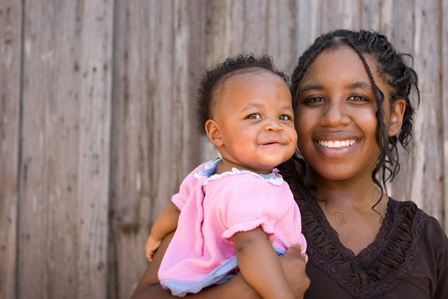 Teenage African American mother holding her daughter.